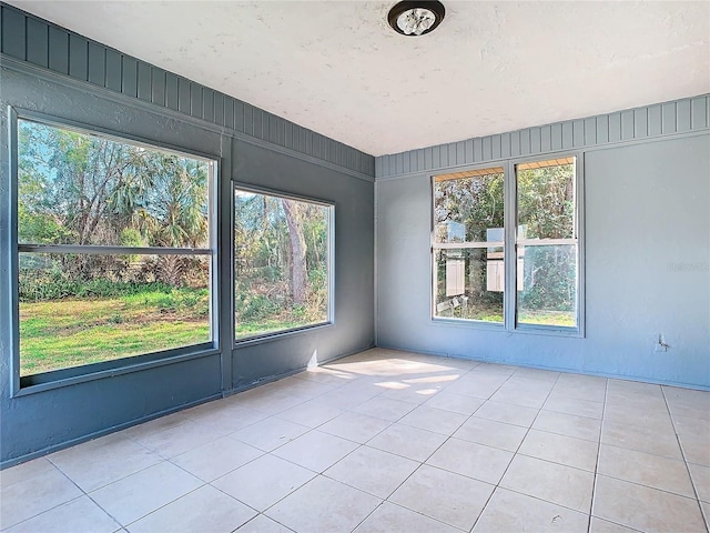 empty room with a wealth of natural light and light tile patterned floors