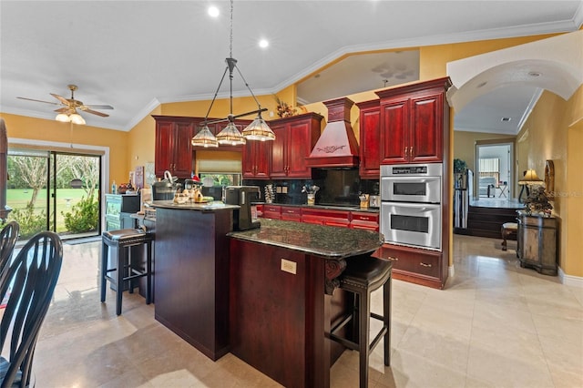 kitchen with custom exhaust hood, a kitchen breakfast bar, a center island, and stainless steel double oven