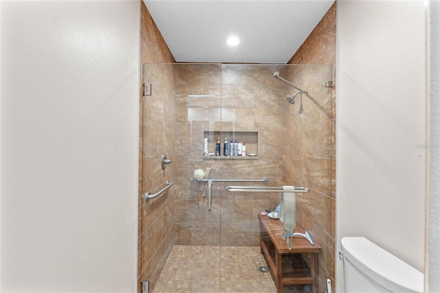 bathroom featuring a shower with shower door and toilet