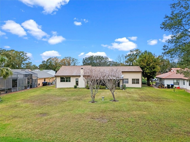 back of house featuring a lawn and glass enclosure