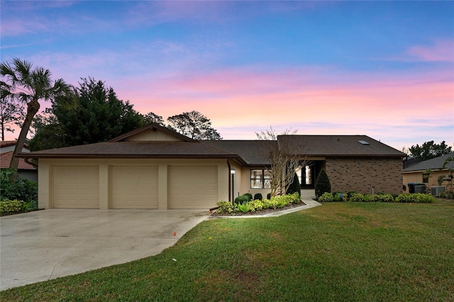 ranch-style house featuring a garage, central AC unit, and a lawn