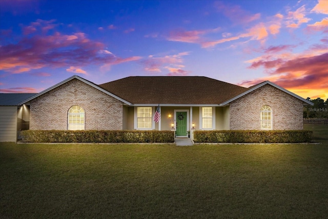 single story home with brick siding and a lawn