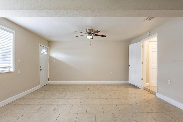 empty room featuring ceiling fan, visible vents, and baseboards