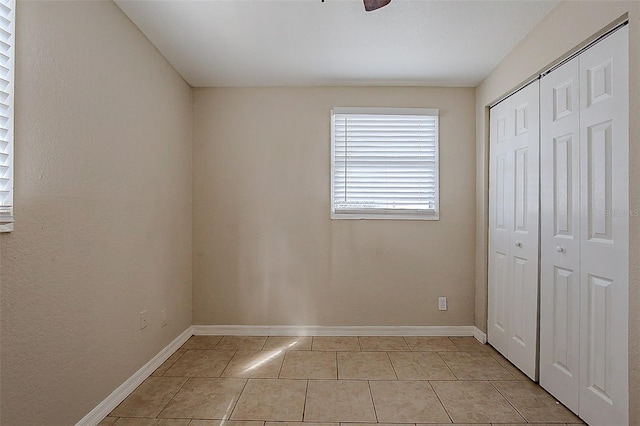 unfurnished bedroom featuring light tile patterned floors, baseboards, and a closet