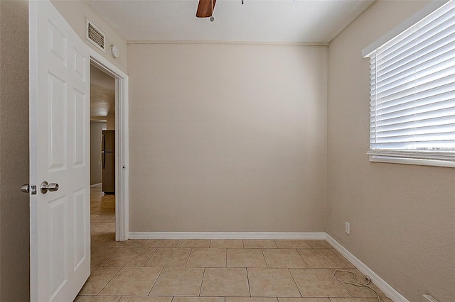 unfurnished room with ceiling fan, light tile patterned flooring, visible vents, and baseboards