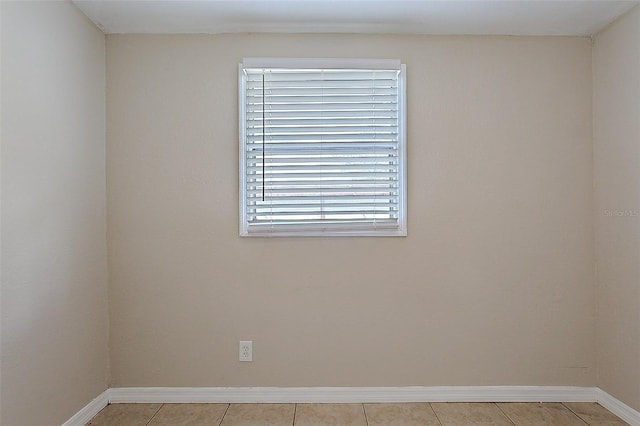 empty room with baseboards and light tile patterned floors