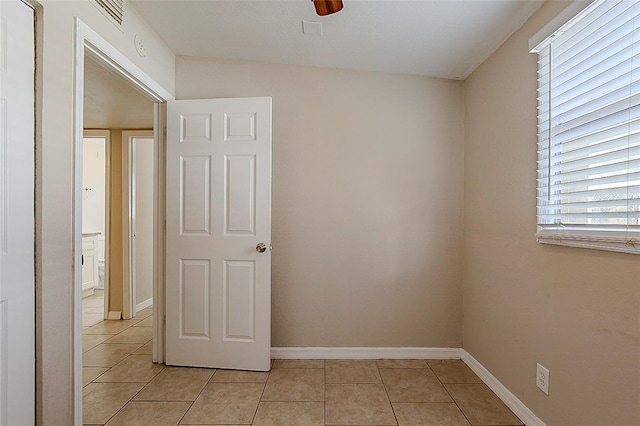 unfurnished room featuring a ceiling fan, baseboards, and light tile patterned floors