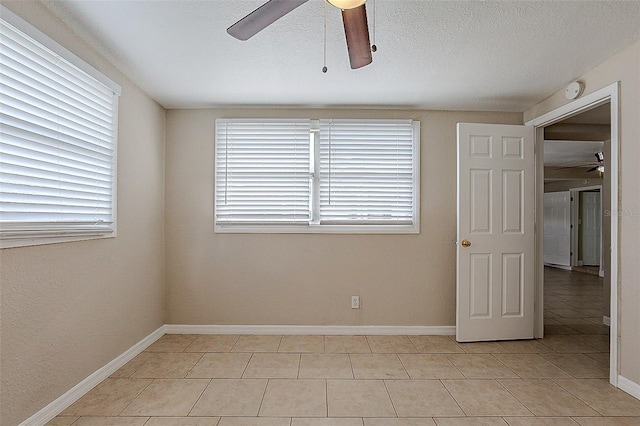 empty room featuring a textured ceiling, baseboards, and a ceiling fan