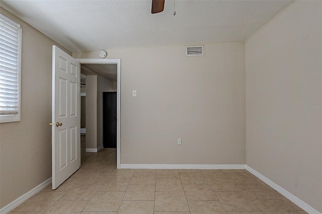 spare room featuring a ceiling fan, baseboards, and light tile patterned floors