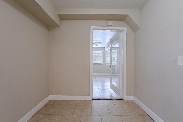 hall featuring baseboards and light tile patterned floors