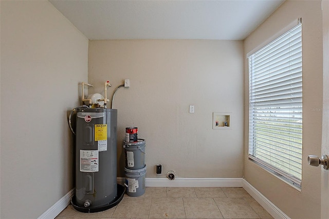 clothes washing area featuring laundry area, plenty of natural light, light tile patterned floors, hookup for a washing machine, and water heater