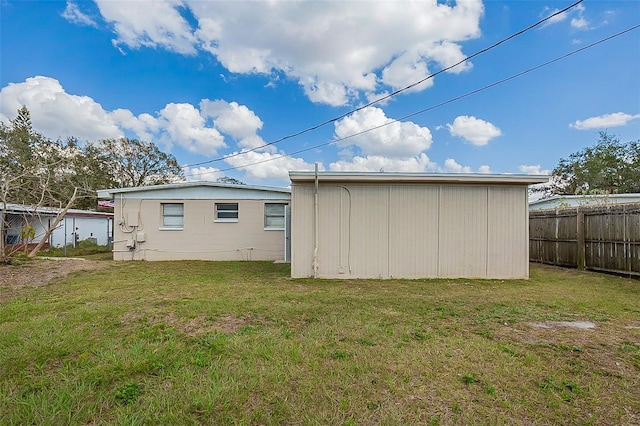 back of house with a yard, fence, and an outdoor structure