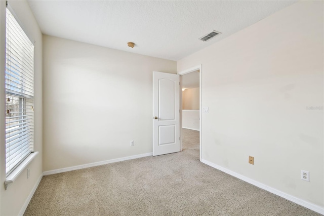 carpeted spare room featuring a textured ceiling