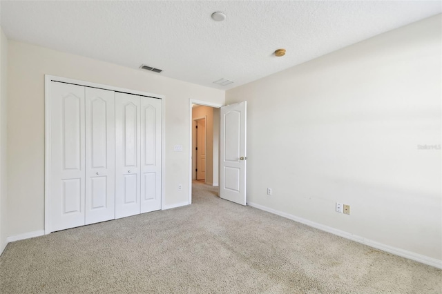 unfurnished bedroom with light colored carpet, a textured ceiling, and a closet