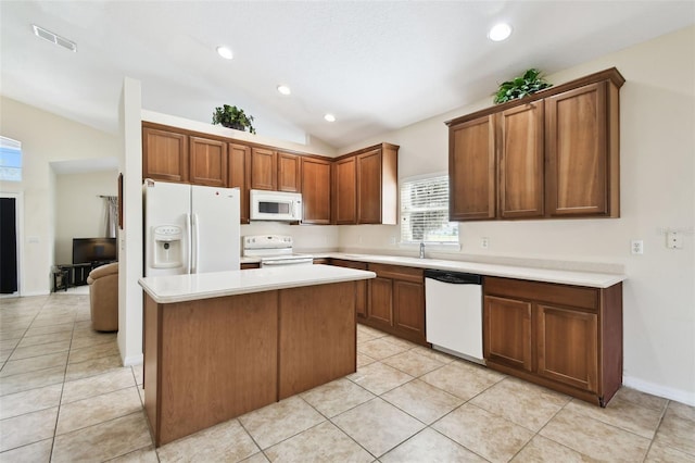 kitchen with light tile patterned floors, white appliances, vaulted ceiling, and a center island