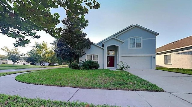 view of front of house with a front lawn, concrete driveway, an attached garage, and stucco siding