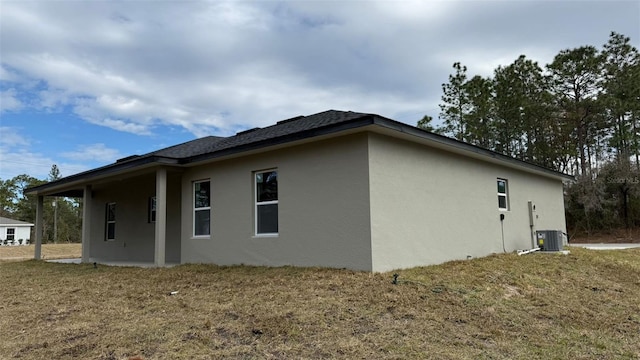 view of side of property featuring a yard and central AC