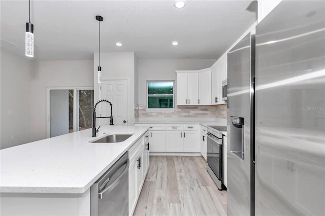 kitchen featuring appliances with stainless steel finishes, decorative light fixtures, sink, and white cabinets