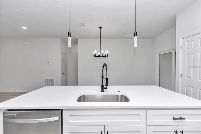 kitchen featuring sink, white cabinetry, stainless steel dishwasher, pendant lighting, and a kitchen island with sink