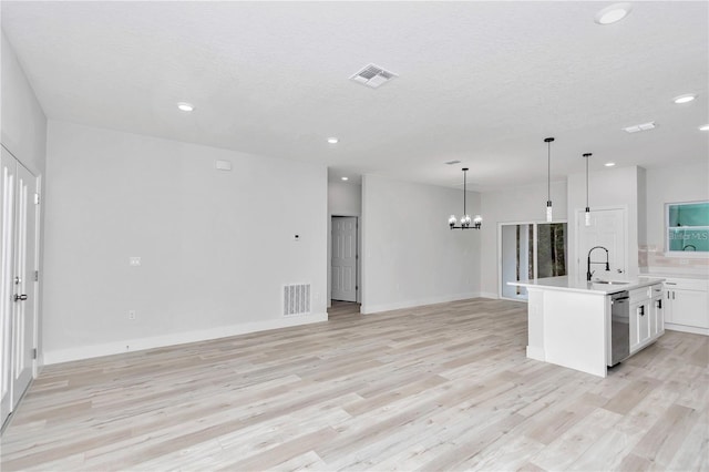 kitchen with pendant lighting, sink, a kitchen island with sink, white cabinets, and stainless steel dishwasher