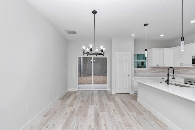 kitchen with tasteful backsplash, sink, decorative light fixtures, and white cabinets