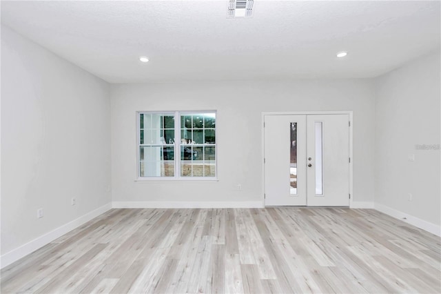 empty room with french doors and light hardwood / wood-style flooring