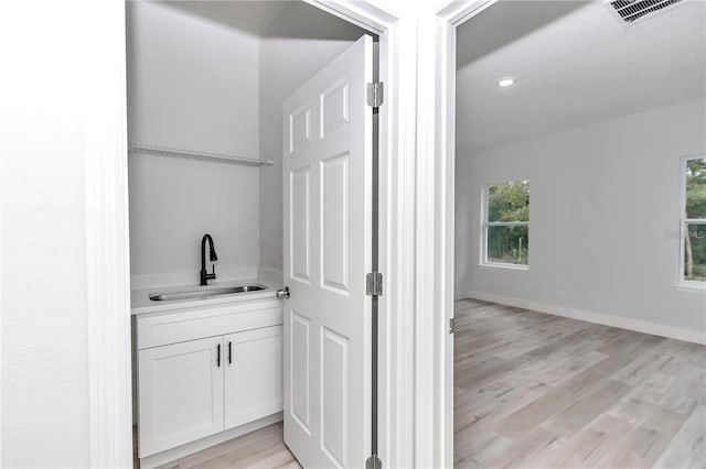 bar featuring light wood-type flooring, sink, and white cabinets