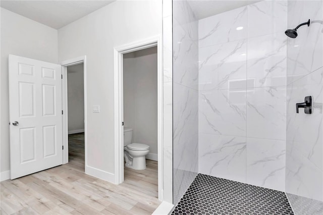 bathroom featuring hardwood / wood-style floors, toilet, and tiled shower