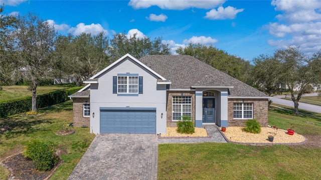 traditional-style house with a garage, brick siding, decorative driveway, and a front yard