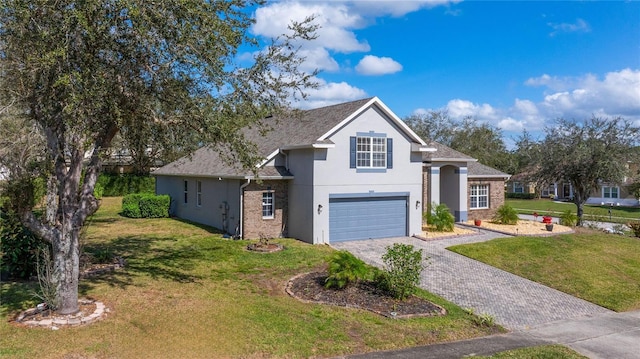 traditional-style house featuring an attached garage, roof with shingles, decorative driveway, stucco siding, and a front yard