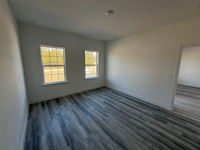 spare room featuring baseboards and dark wood-style flooring