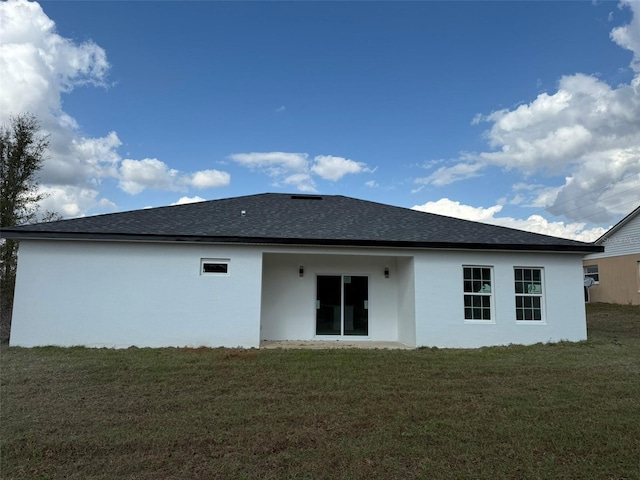 rear view of property with a shingled roof, a lawn, and stucco siding