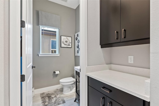 half bathroom with toilet, vanity, and baseboards