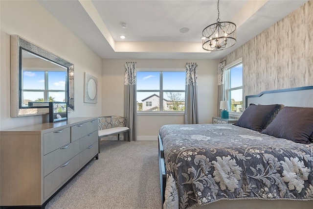 bedroom featuring a raised ceiling, light colored carpet, a notable chandelier, and baseboards