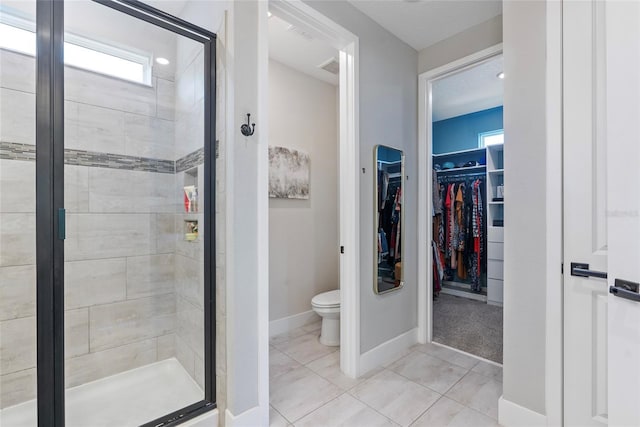 full bathroom with toilet, baseboards, a shower stall, tile patterned floors, and a walk in closet