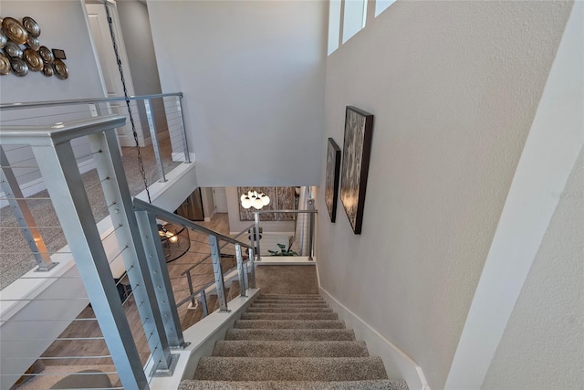 stairway featuring a towering ceiling and baseboards