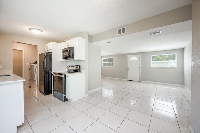 kitchen with white cabinets, light tile patterned floors, a textured ceiling, and black appliances