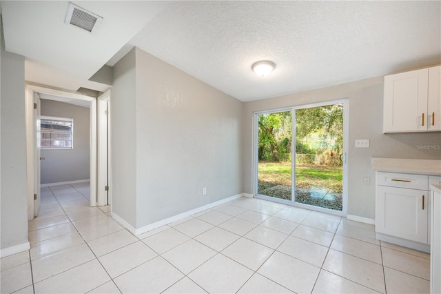 unfurnished dining area with light tile patterned floors and a textured ceiling