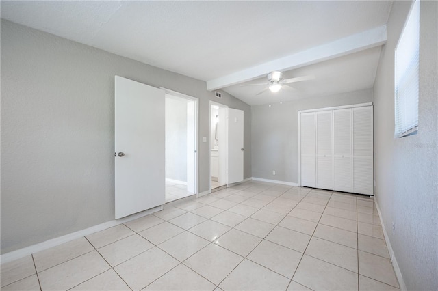 unfurnished bedroom featuring ceiling fan, light tile patterned floors, lofted ceiling with beams, and a closet