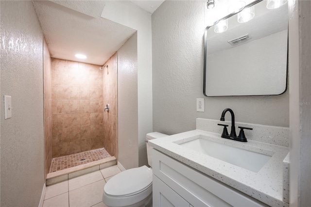 bathroom featuring vanity, tiled shower, toilet, and tile patterned floors