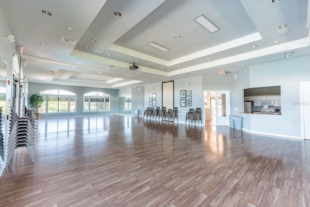 interior space featuring light wood finished floors, a raised ceiling, visible vents, and baseboards