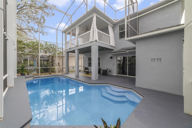 outdoor pool with a lanai, ceiling fan, and a patio