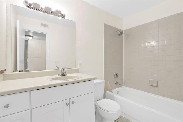 full bathroom featuring tiled shower / bath, vanity, and toilet