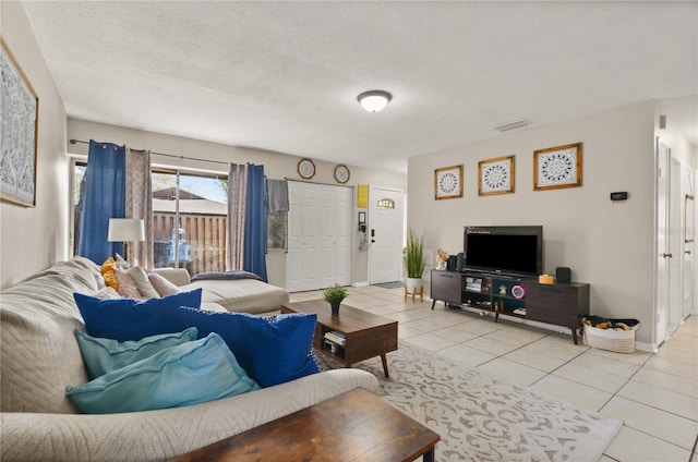 living room with light tile patterned floors, baseboards, visible vents, and a textured ceiling