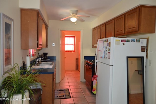 kitchen with sink, light tile patterned floors, range with gas stovetop, white fridge, and ceiling fan