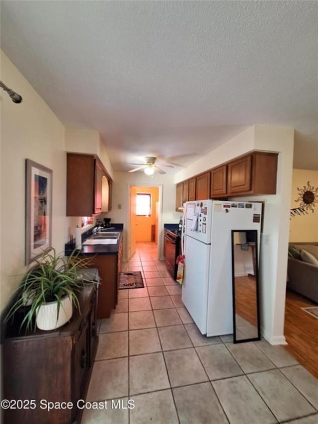 kitchen with a textured ceiling, light tile patterned flooring, ceiling fan, and white fridge