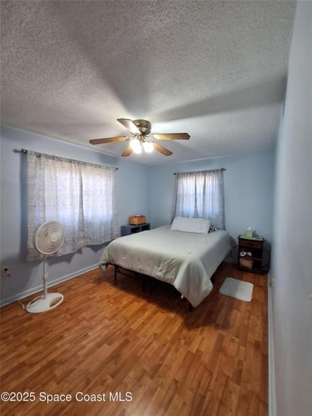 bedroom with ceiling fan, hardwood / wood-style floors, and a textured ceiling