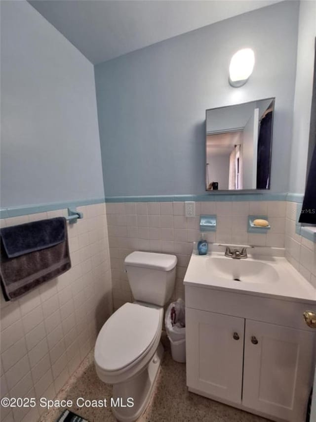 bathroom featuring vanity, toilet, and tile walls