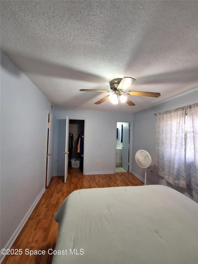 bedroom with wood-type flooring, ceiling fan, a textured ceiling, ensuite bath, and a closet