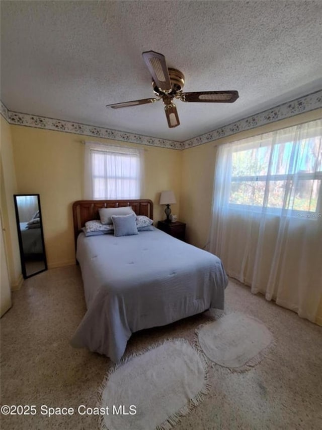 bedroom with ceiling fan and a textured ceiling